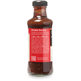 A bottle of Hoisin Sauce from The Kitchen of Kame, featuring a dark brown sauce visible through the glass and a red label with white text.