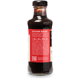 A bottle of KAME Asian Master Brand Oyster Sauce shown from the back, featuring a red label with white text and a black cap, on a white background.