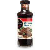 A bottle of Kame Oyster Sauce, 11 fl oz (320 mL), featuring a dark brown sauce inside, a black cap, and a label with a red top section and an image of oyster sauce on beef with broccoli.