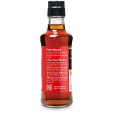 A bottle of Kome Fish Sauce, showing the back label and amber liquid inside, on a white background.