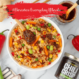 Fried rice with vegetables and a jar of 'Kame Chili Crisp' on a marble surface.
